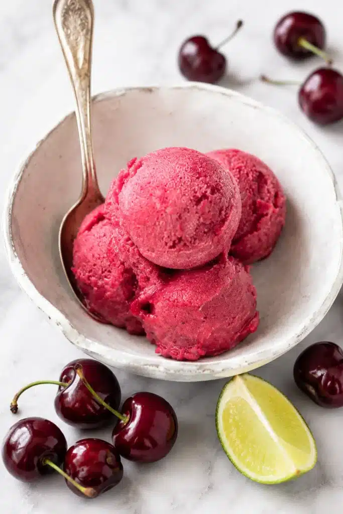 Fresh Cherry Sorbet scoops in a white bowl with cherries
