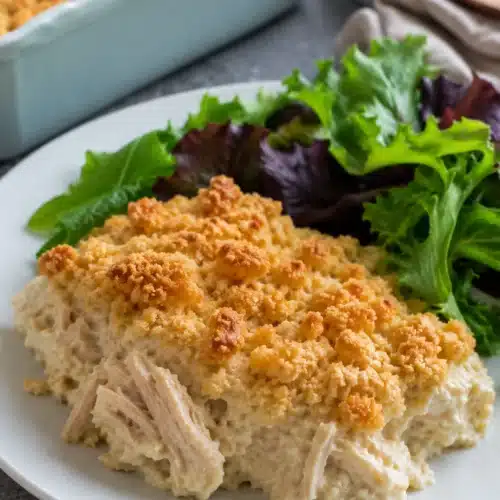 Ritz Cracker Chicken Casserole served with fresh green salad on a white plate